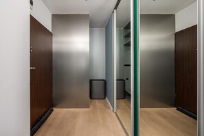 Ein Korridor mit Holztüren, einem Mülleimer und einer Schiefspiegeltür zum Kleiderschrank.