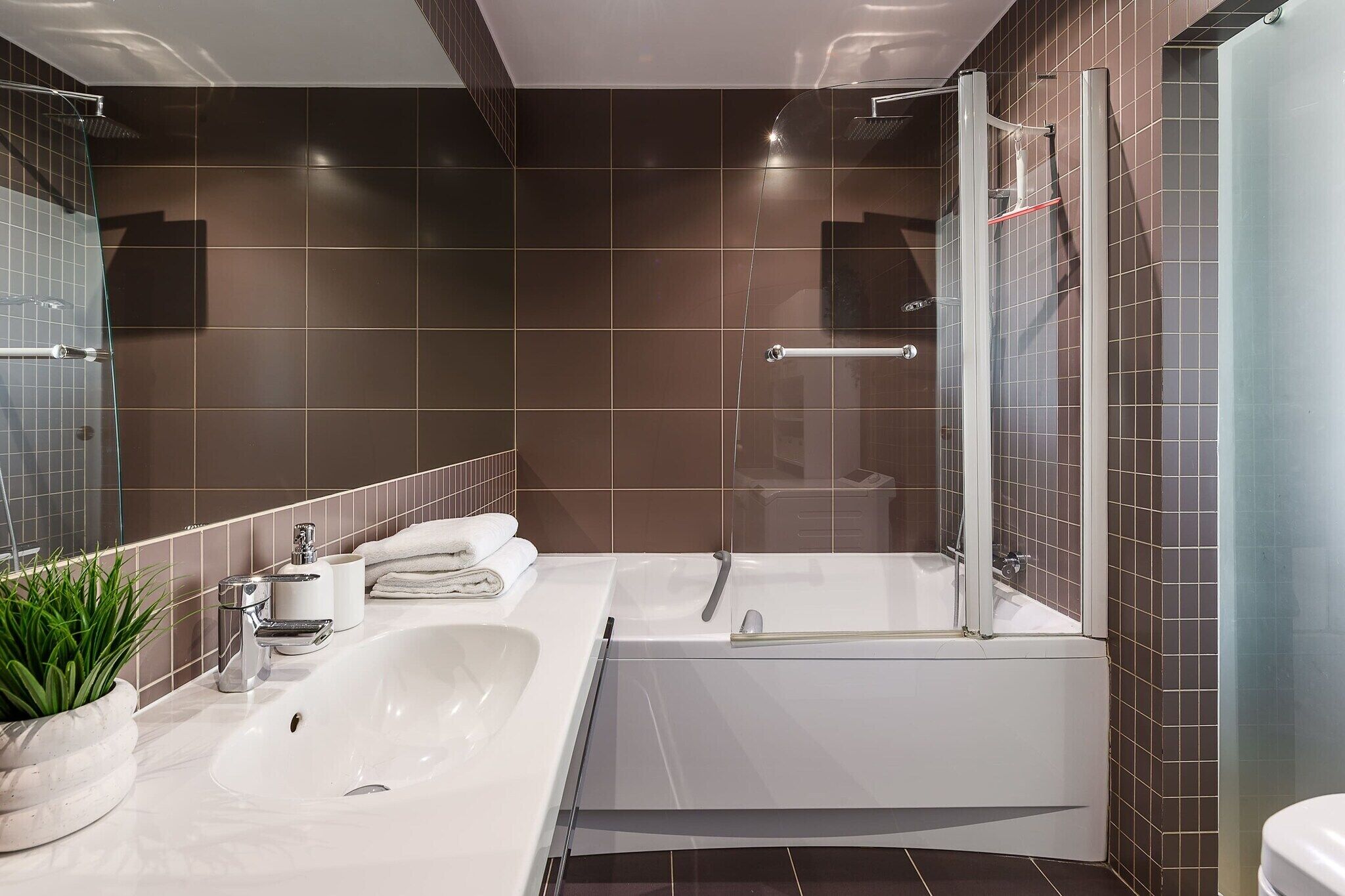 A modern bathroom with a large bathtub, a glass-enclosed shower, and a white sink.