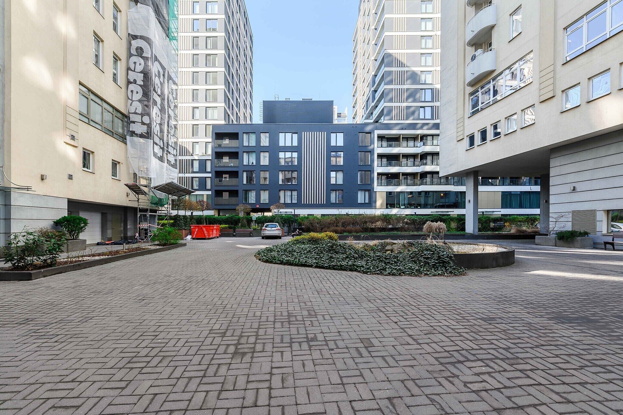 Un moderno edificio residencial con un patio empedrado, rodeado de altos apartamentos.
