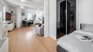 Eine moderne Wohnung mit Essbereich, Küche und einem Schlafzimmer mit großem Bett und Nachttisch.