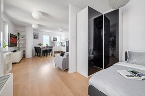 Eine moderne Wohnung mit Essbereich, Küche und einem Schlafzimmer mit großem Bett und Nachttisch.