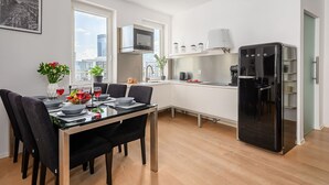 Eine moderne Küche mit Essbereich, einem schwarzen Kühlschrank und Blick auf die Stadt.