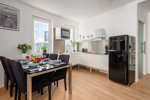 Eine moderne Küche mit Essbereich, einem schwarzen Kühlschrank und Blick auf die Stadt.