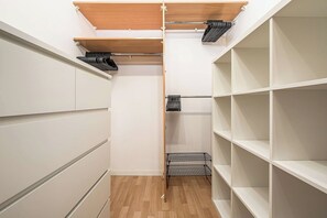 Ein begehbarer Kleiderschrank mit offenen Regalen, einer Holzbalkendecke und einem Metallgestell.