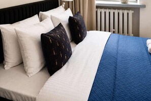 A neatly made bed with white and navy pillows, a blue quilt, and a white headboard. - Quiet City Apartment for 4 (Warszawa)
