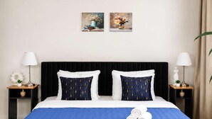 Ein Hotelzimmer mit einem großen Bett, zwei Nachttischen, zwei Lampen und zwei Wandbildern.