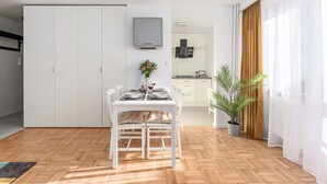 A modern kitchen with a dining area, white cabinetry, and a large window with curtains. - House in Porspoder by Plage du Bourg Beach (Warszawa 2)