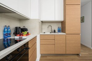 Une cuisine moderne avec des armoires blanches, un plan de travail en bois et un évier encastré.