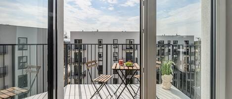 A balcony with a table, chairs, and a potted plant.