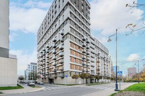 A multi-story residential building with balconies, a pedestrian crossing, and a clear sky. - Beautiful Flat with Garage (Łódź)