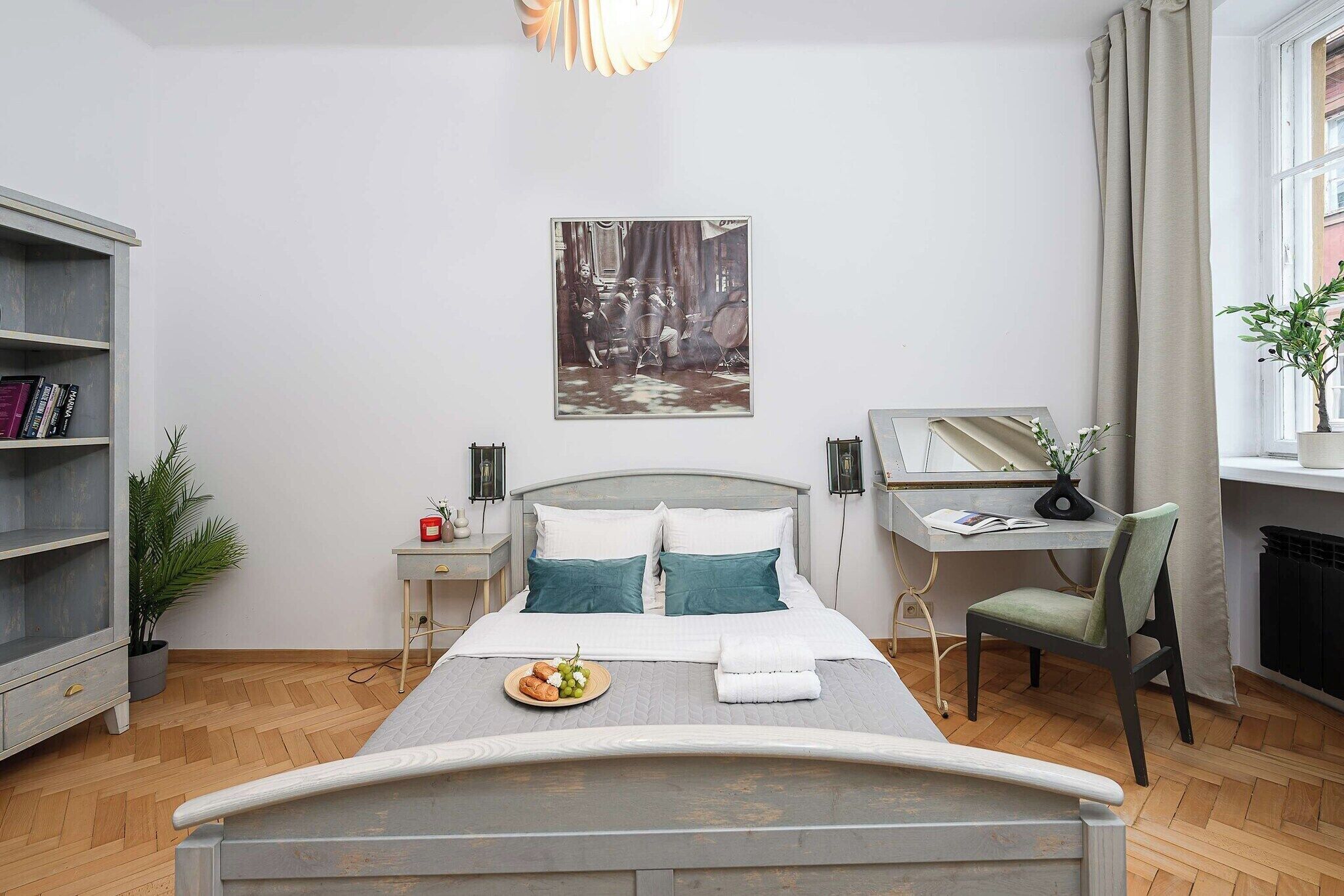 Quarto com cama, escrivaninha, estante e um quadro na parede.