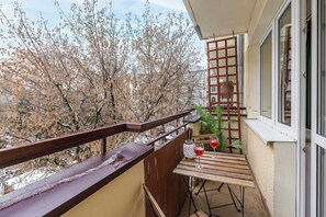 Ein Balkon mit Holztisch, zwei Weingläsern und einem Blumentopf.
