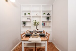 Un coin repas avec une table blanche dressée pour six personnes, entourée de chaises en bois.