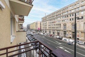 A street view with a building on the left and a row of parked cars on the right. - Central Warsaw Apartment with 2 Balconies (Warszawa 2)