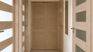 Un pasillo con una puerta doble que da a una habitación.