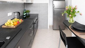 Una cocina moderna con cubierta negra, electrodomésticos de acero inoxidable y un frutero.