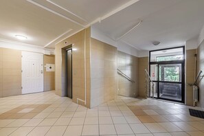 A clean, well-lit hallway with a tiled floor, a door, an elevator, and a glass door leading outside. - Modern Coastal Home with Scenic Terrace Views (Warszawa)
