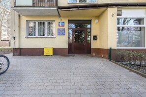 A building entrance with a paved driveway, a yellow utility box, and a door with a window. - Modern Coastal Home with Scenic Terrace Views (Warszawa)