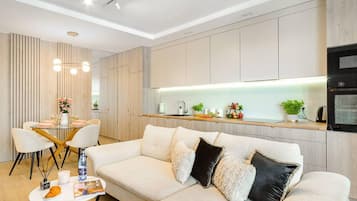 Ein modernes Wohnzimmer mit Sofa, Esstisch und Küchenbereich.