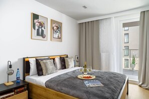 Ein Hotelzimmer mit einem großen Bett, einem Nachttisch mit Lampe, einer Zeitschrift und einer Weinflasche.