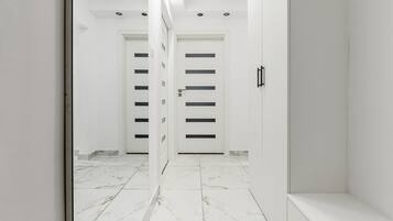 A hallway with white walls, a tiled floor, and two doors with horizontal black stripes.