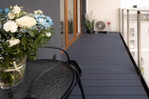 A balcony with a table, a vase of flowers, a potted plant, and a wall-mounted fan. - Character house with Spa and seaview (Łódź)
