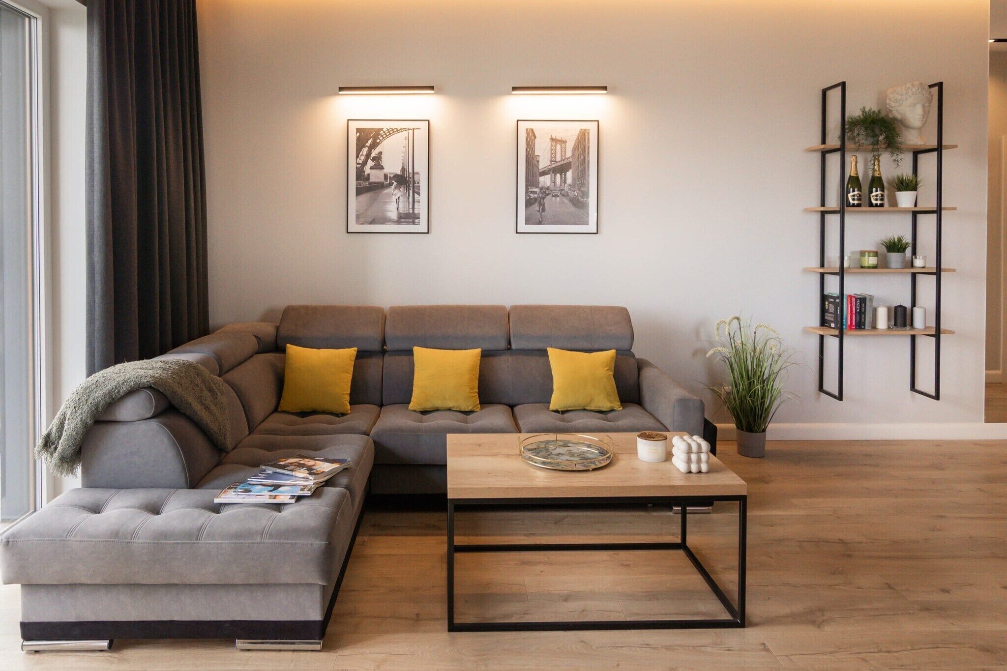 Un salon moderne avec un canapé d’angle, une table basse et deux tableaux encadrés accrochés au mur.