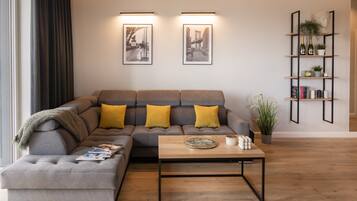 Un salon moderne avec un canapé d’angle, une table basse et deux tableaux encadrés accrochés au mur.