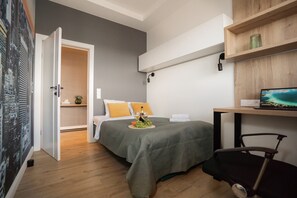A modern bedroom with a bed, bedside table, and a desk with a laptop. - Charming Apartment with Premium Furnishings in Łódź (Łódź)