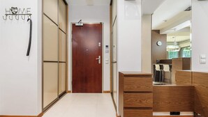 A hallway with a wooden door, a coat rack with hooks, and a wooden cabinet with drawers. - Parkside Flat with Private Garage (Łódź)