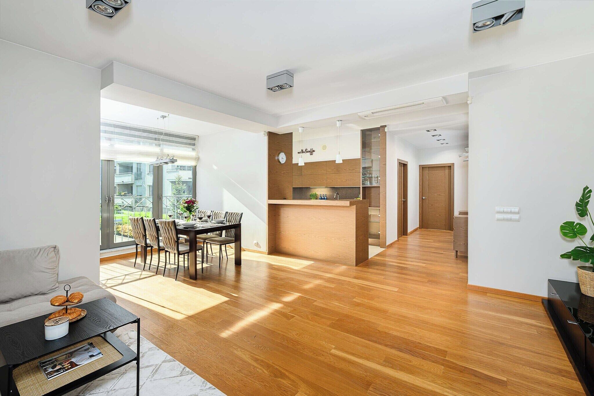 A modern living space with a dining area, kitchen, and a view of the outdoors.