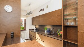 A modern kitchen with wooden cabinetry, a built-in sink, and a countertop with a toaster and a plant. - Parkside Flat with Private Garage (Łódź)