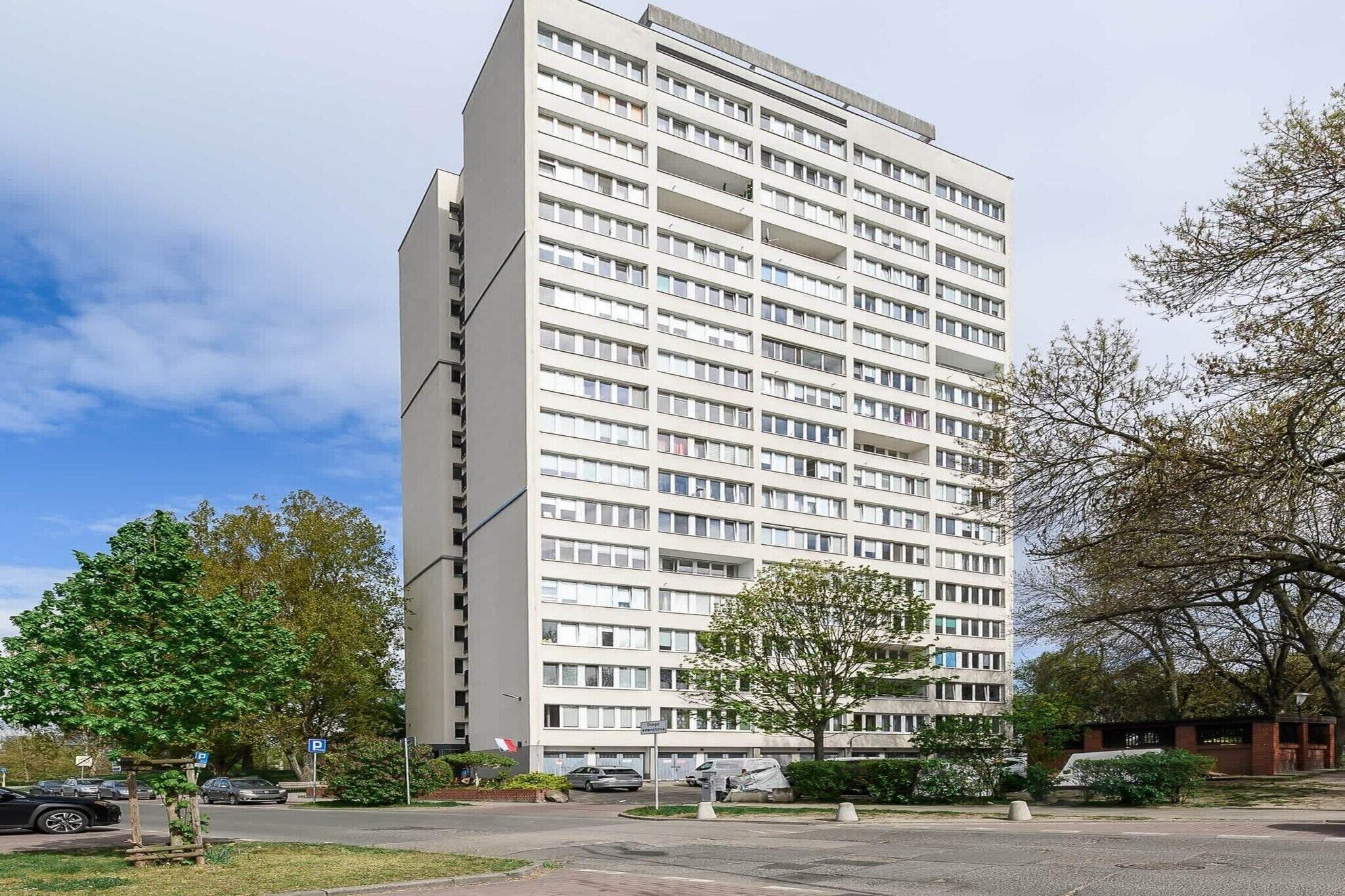 A multi-story building with a uniform facade, likely a hotel or apartment complex, with a parking lot in the foreground.