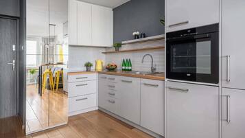 Een moderne keuken met witte kasten, een zwarte oven en een houten aanrecht.