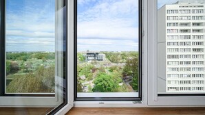 A window with a view of a building complex and surrounding greenery. - Riverside Flat near Center (Warszawa)