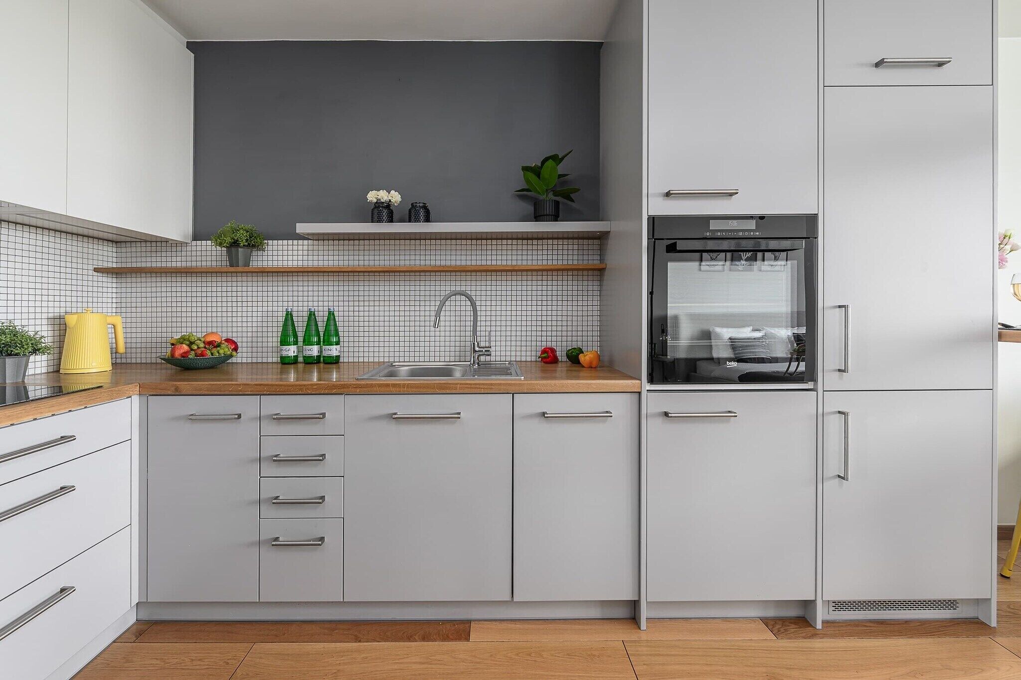 A modern kitchen with white cabinets, a wooden countertop, and a built-in refrigerator.