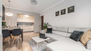 Uma sala de estar moderna com um sofá, mesa de centro e área de jantar com cadeiras e uma mesa posta para uma refeição.