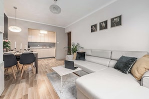 Ein modernes Wohnzimmer mit Sofa, Couchtisch und Essbereich mit Stühlen und einem für eine Mahlzeit gedecktem Tisch.