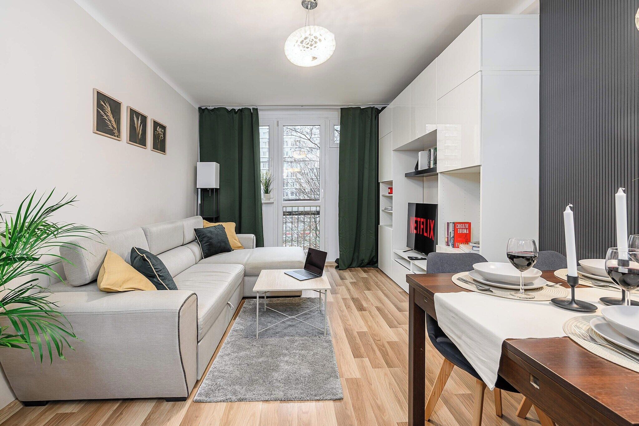 A modern living room with a grey sofa, a coffee table, and a dining area with a table set for two.