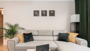 Uma sala de estar moderna com um sofá modular cinza, uma mesa de centro com um laptop e uma planta em vaso.