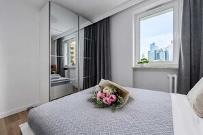 A modern bedroom with a large bed, a city view, and a mirror. - Flat near Warszawa Centralna (Warszawa)