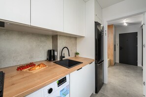 Eine moderne Küche mit Holzarbeitsplatte, Edelstahlgeräten und einem eingebauten Geschirrspüler.