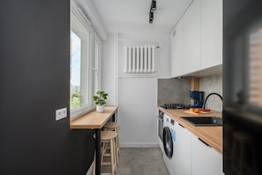 A compact kitchen with a built-in washing machine, a coffee maker, and a window providing natural light. - Flat near Warszawa Centralna (Warszawa)