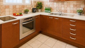 A kitchen with wooden cabinets, a built-in oven, a sink, and a window above the countertop. - Historic City Stay for 4 in Warsaw (Warszawa)