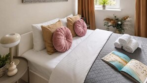 A neatly made bed with a quilted cover, two pillows, and a book on the side. - Historic City Stay for 4 in Warsaw (Warszawa)