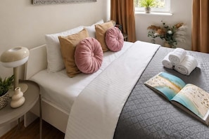 Ein ordentlich bezogenes Bett mit einer gesteppten Decke, zwei Kissen und einem Buch auf der Seite.