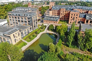 A multi-story building complex with a central courtyard and a small pond. - Home near Historic District (Łódź)
