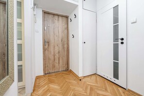 Ein Flur mit einer Holztür, einer weißen Tür mit Griff und einem weißen Schrank mit Griff.