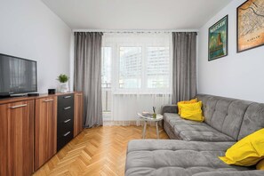 Ein Wohnzimmer mit einer Couch, einem Fernseher, einem kleinen Tisch und einem Schrank.