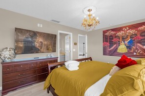 Un dormitorio con una cama grande, un aparador, un espejo y una araña.